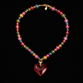 Colorful beaded bracelet with a red heart charm on a black background